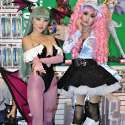 Popular Asian cosplayers Linda Le and Alodia Gosiengfiao pose for the cameras at the 2010 San Diego Comic-Con. Linda cosplays Morrigan Aensland from the video game Darkstalkers. Alodia cosplays Miwako Sakurada from the anime series Paradise Kiss. In the foreground is a copy of the photobook Otacool 2: Worldwide Cosplayers.